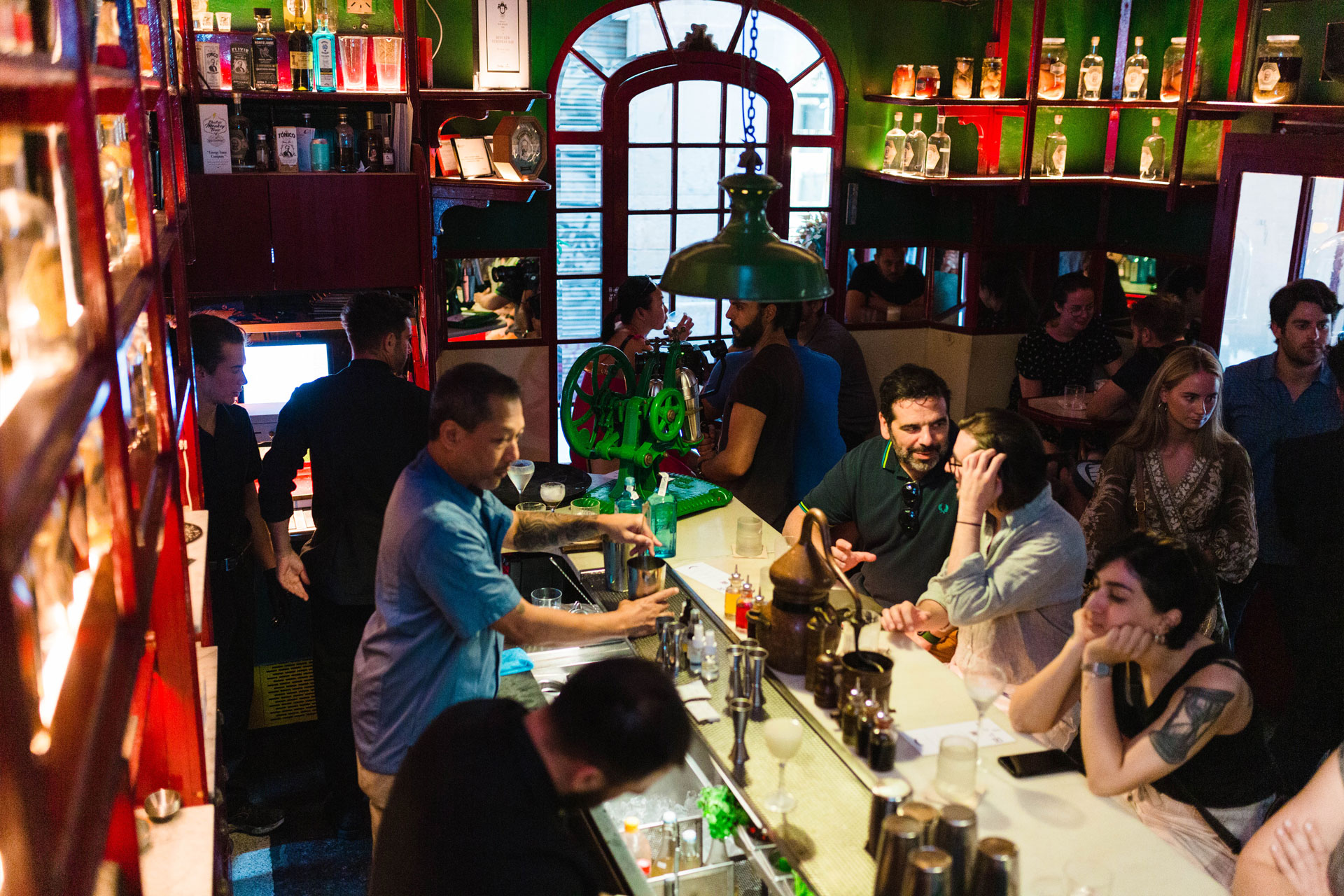 muchas personas en un bar y un coctelero trabajando en la barra